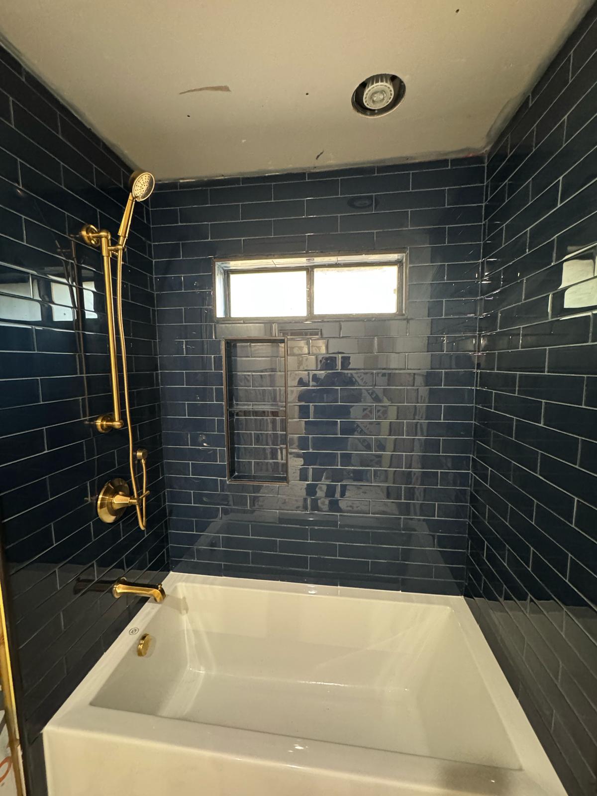 Finished bathroom with navy subway tile and gold fixtures